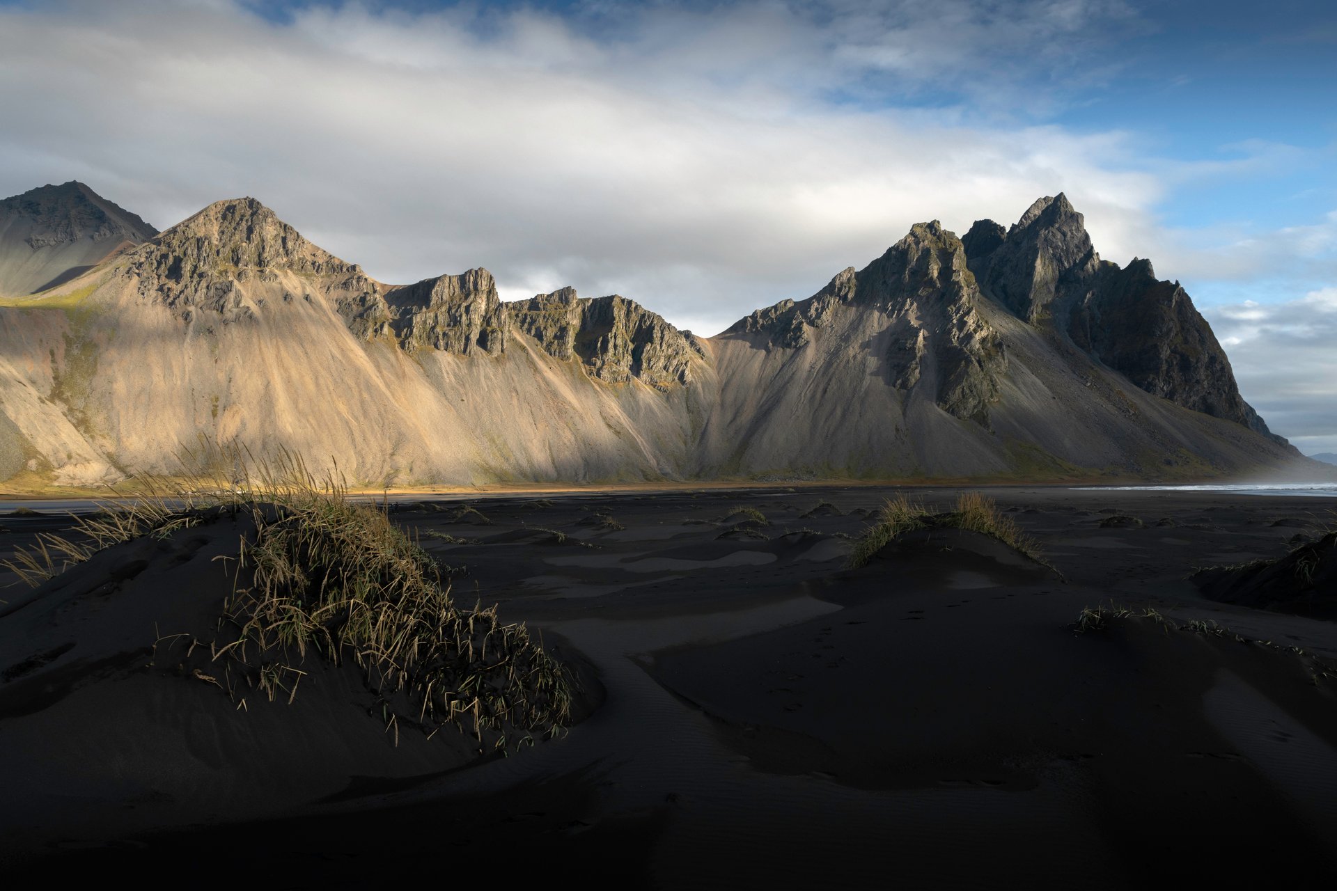 Vestrahorn mountain rising above black sand dunes and reflective tidal flats