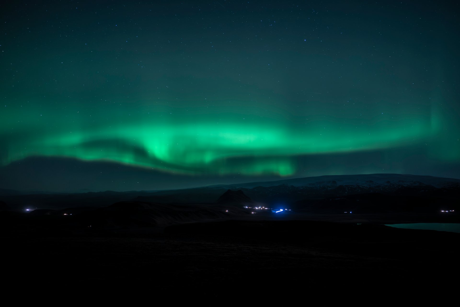 Early aurora display with green lights forming across the horizon