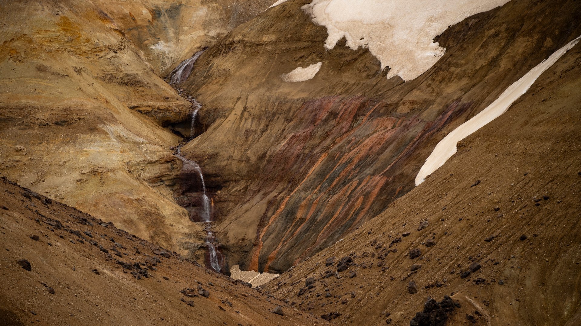 Kerlingarfjöll snow patches next to geothermal steam on a highland road in June, Iceland
