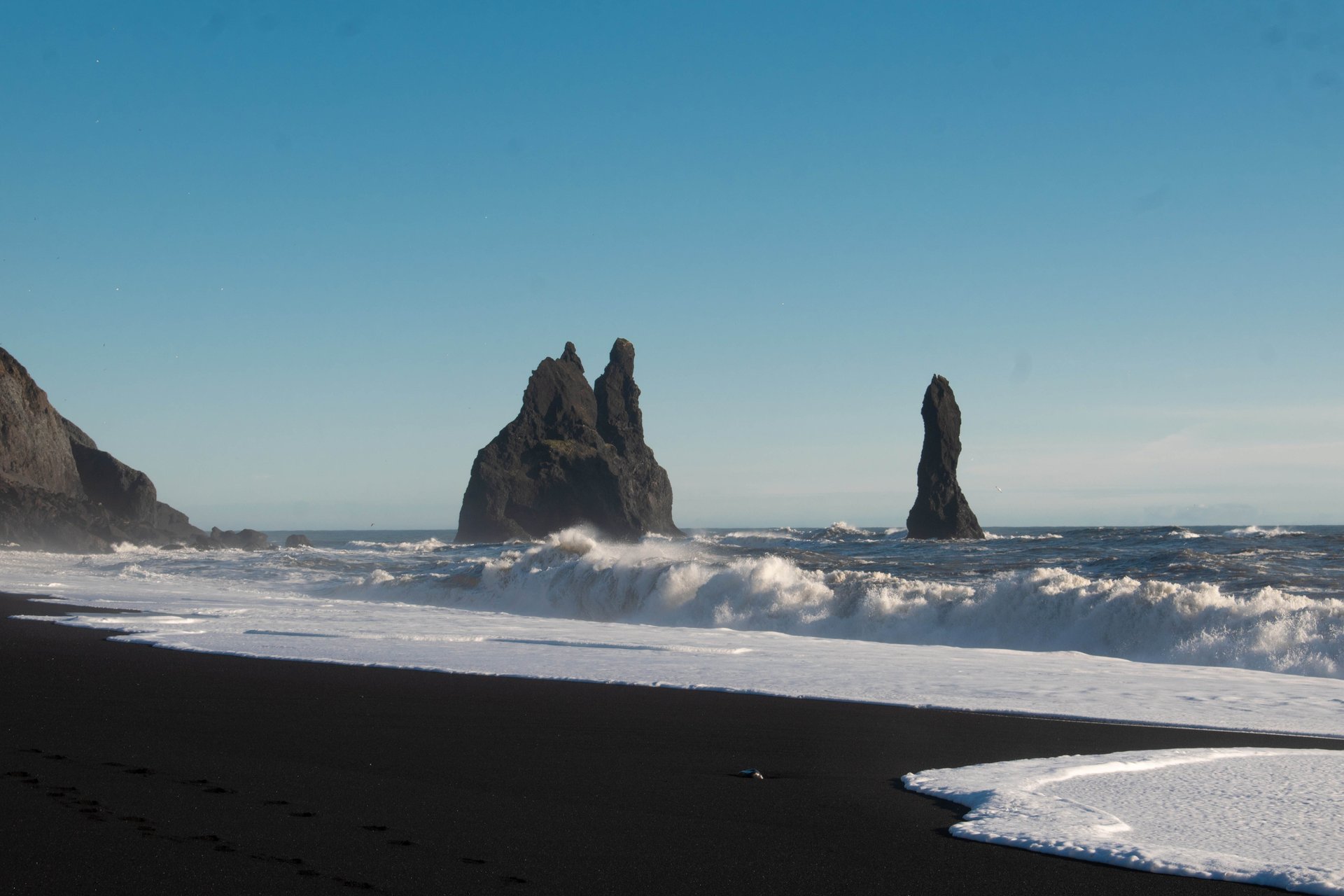 Visitors walking on Reynisfjara black sand beach near the basalt columns