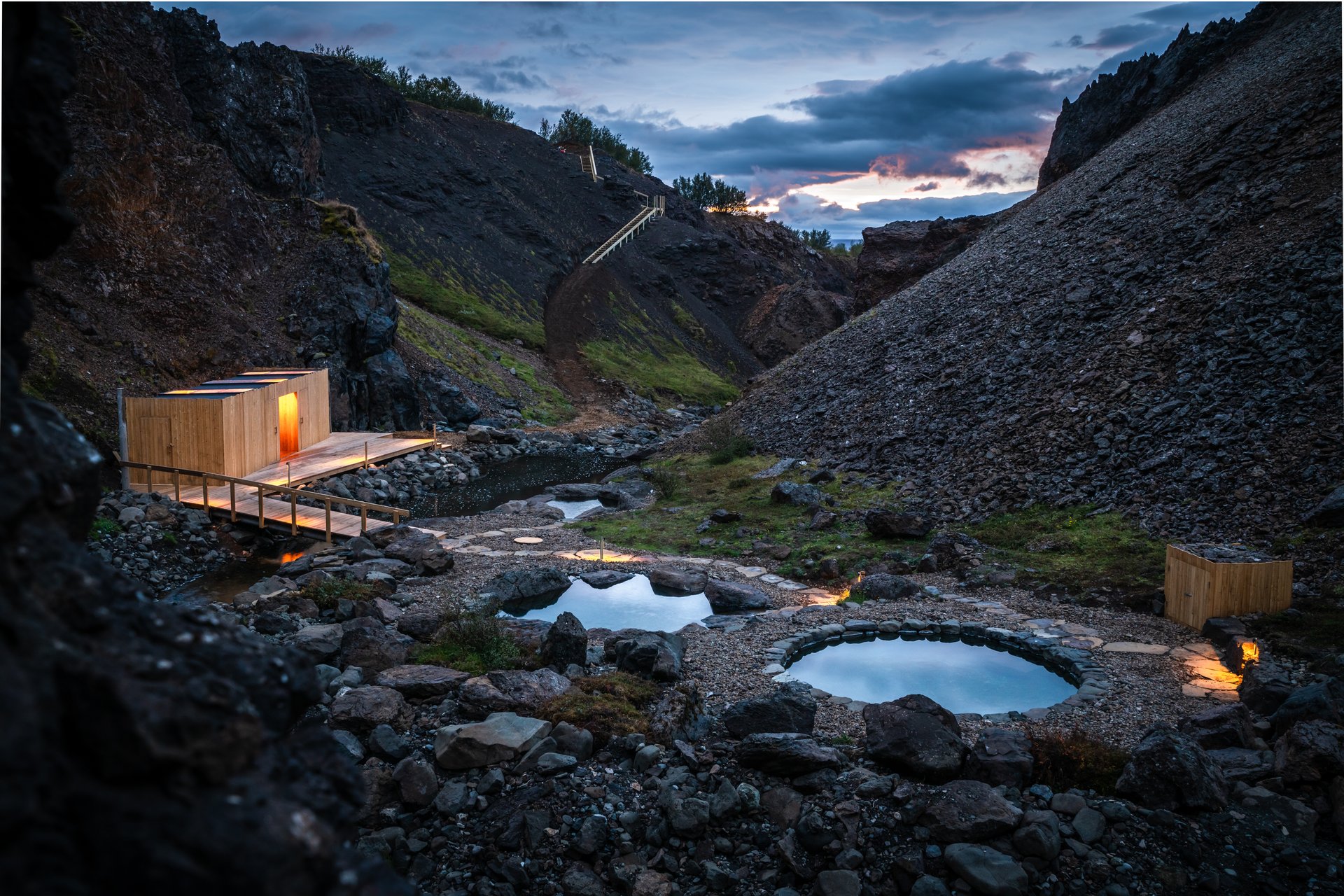 Geothermal pool with dramatic canyon walls and mountain backdrop