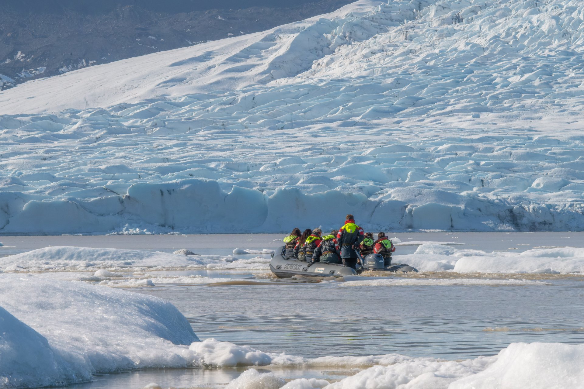 Boat approaching massive blue icebergs at Fjallsárlón Glacier Lagoon