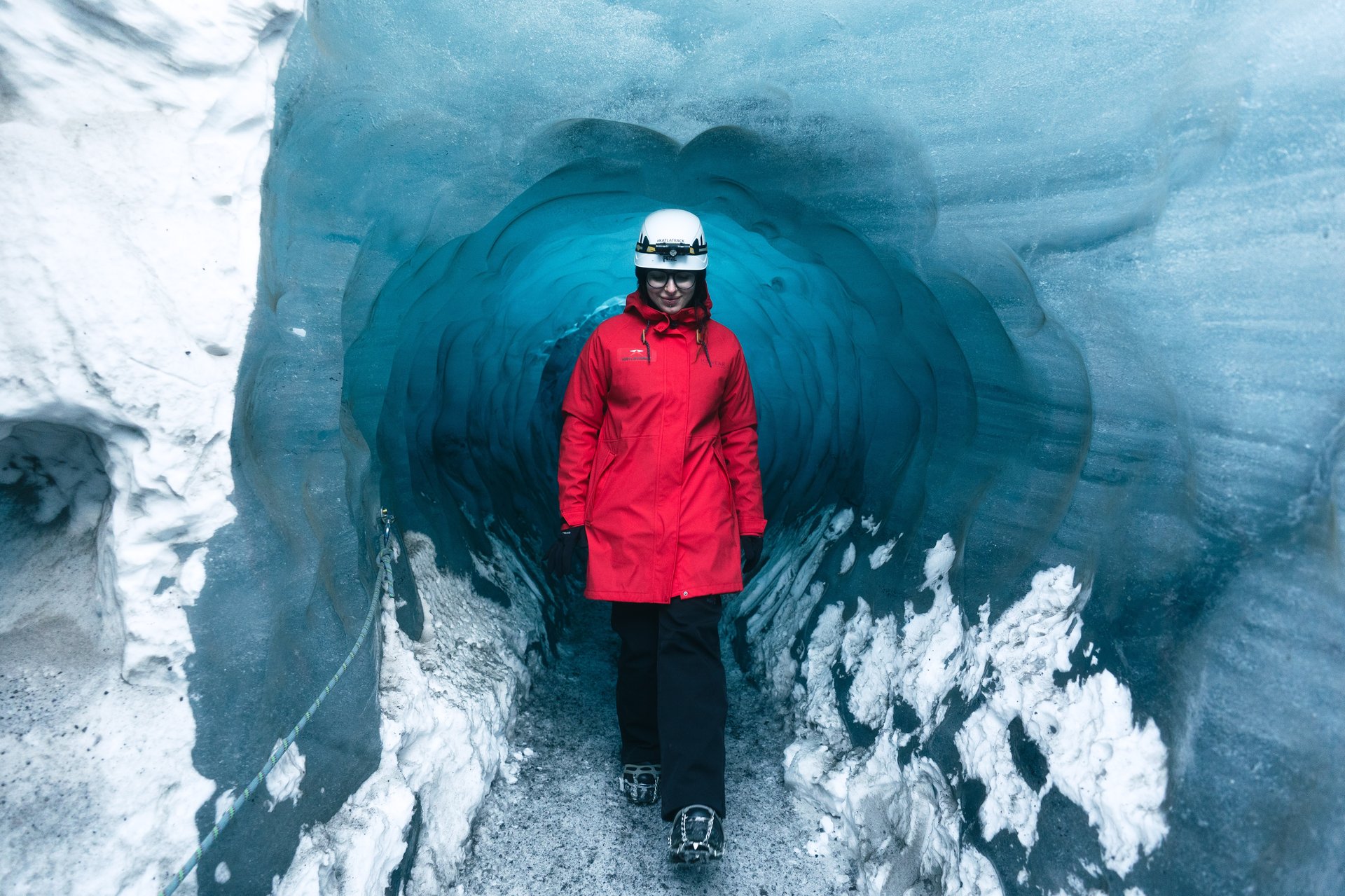 Black volcanic ash layers creating stripes in blue ice cave