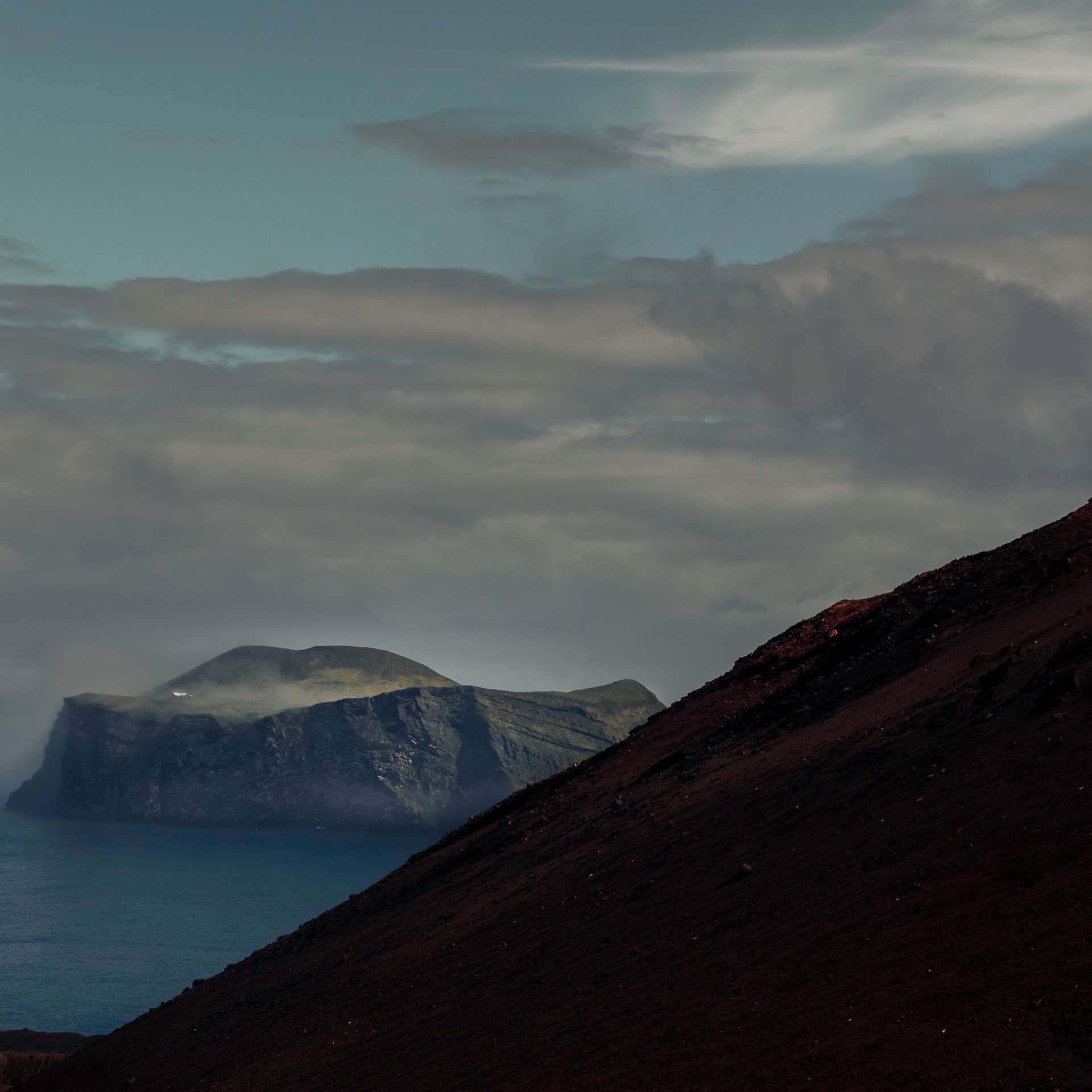 Heimaey harbor town with colorful houses and dramatic volcanic backdrop