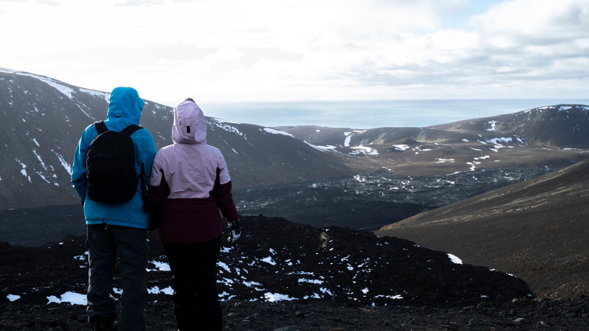 Hikers trekking through fresh lava fields toward Fagradalsfjall volcano crater on the Reykjanes Peninsula