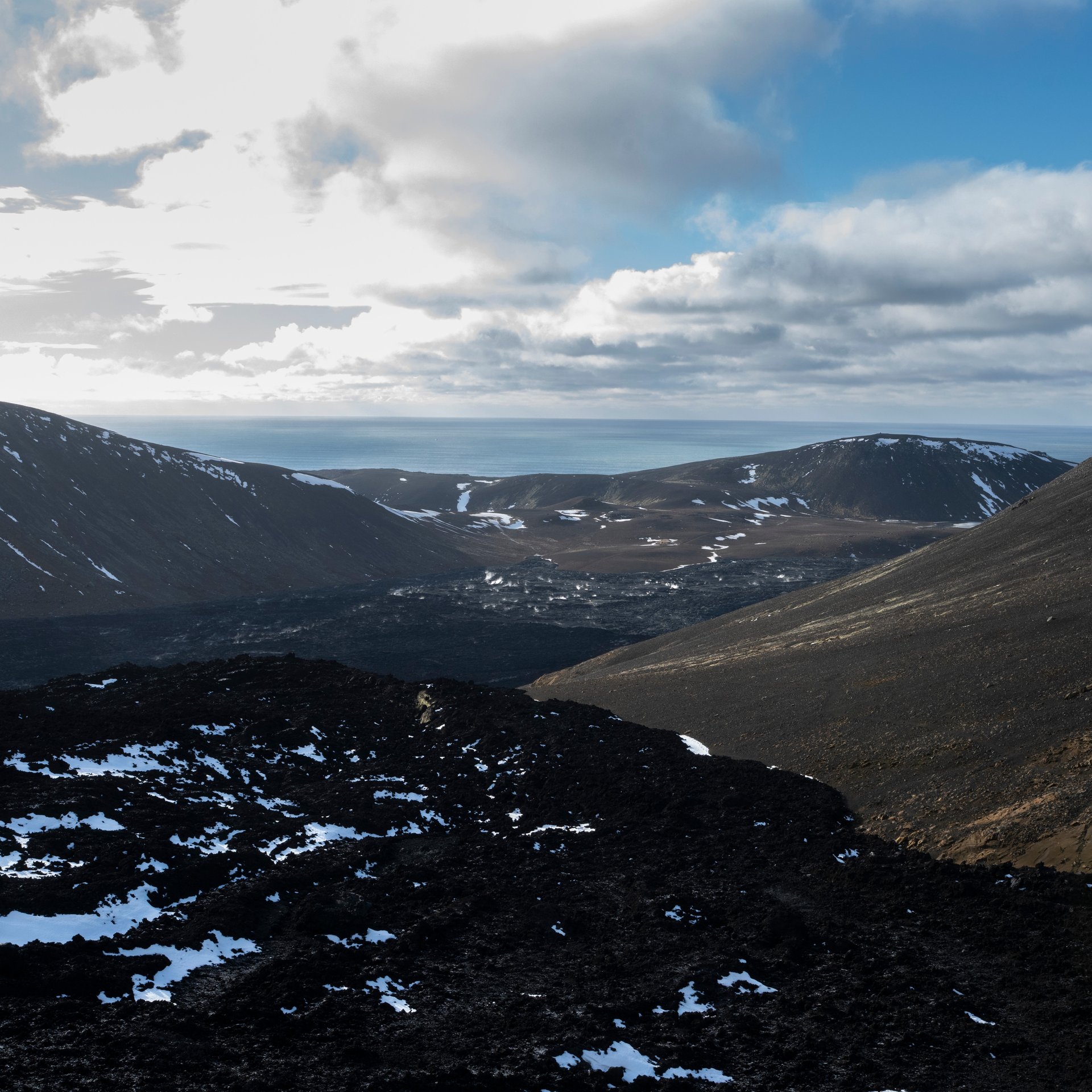 Hikers on the Fagradalsfjall volcano trail with fresh lava fields and crater viewpoint