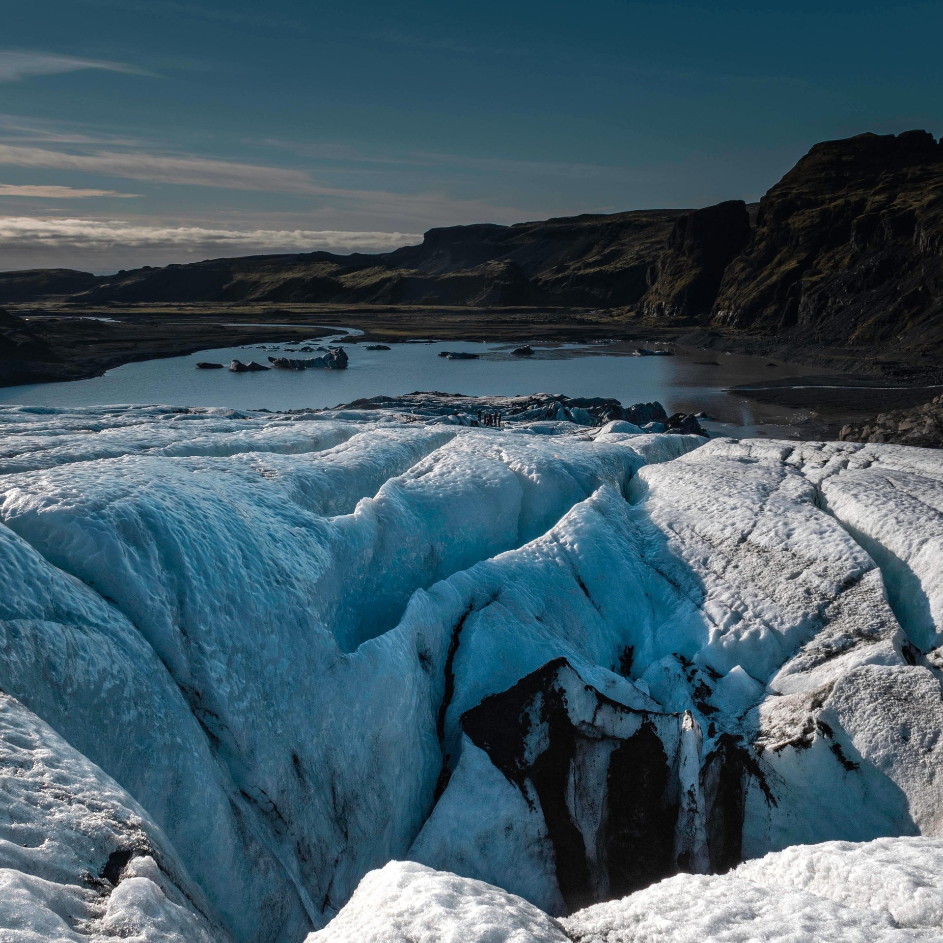 Guides glaciaires préparant l'équipement à la base du glacier Sólheimajökull avec formations de glace en arrière-plan