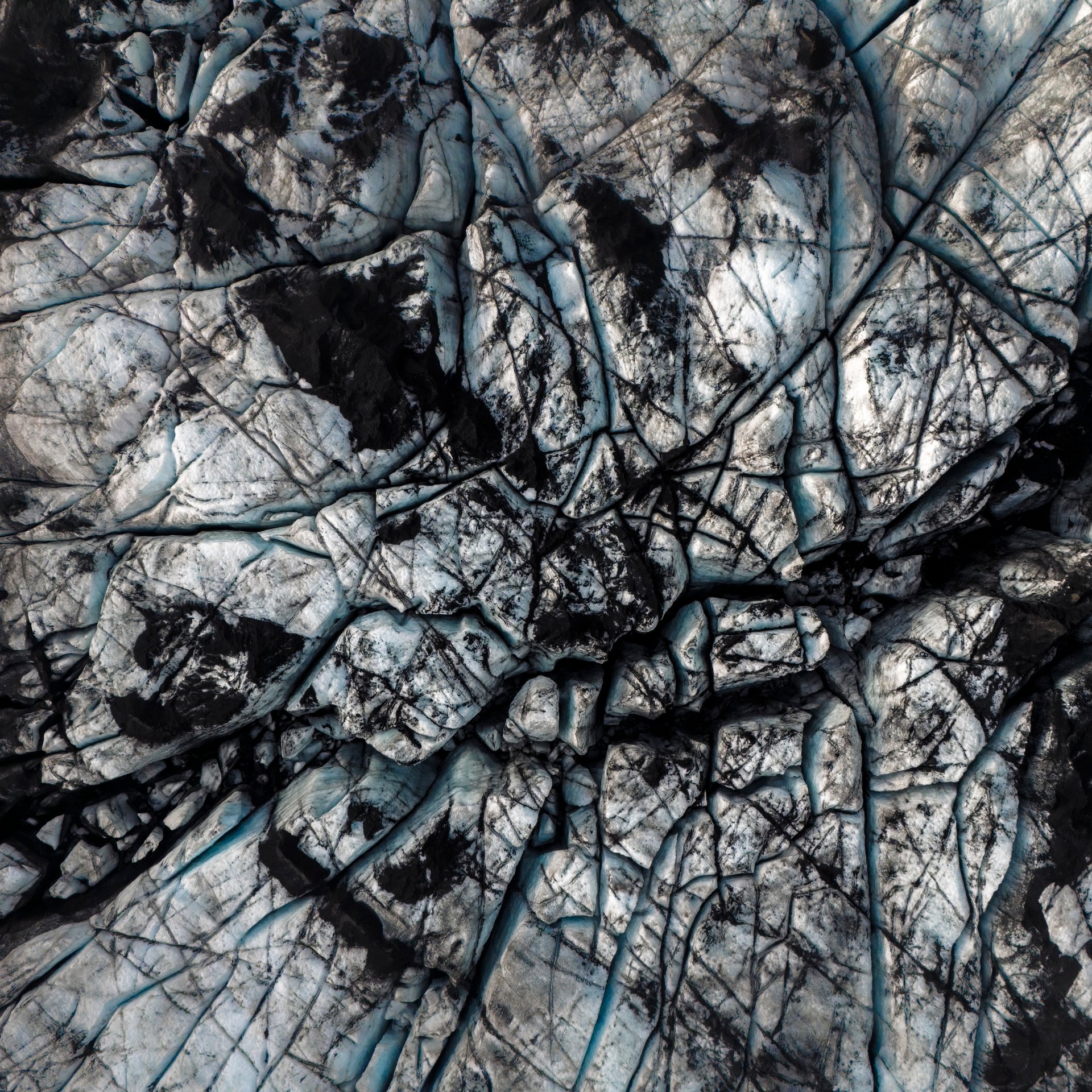 Randonneurs avec crampons explorant les crevasses bleues profondes et formations de glace sur le glacier Sólheimajökull