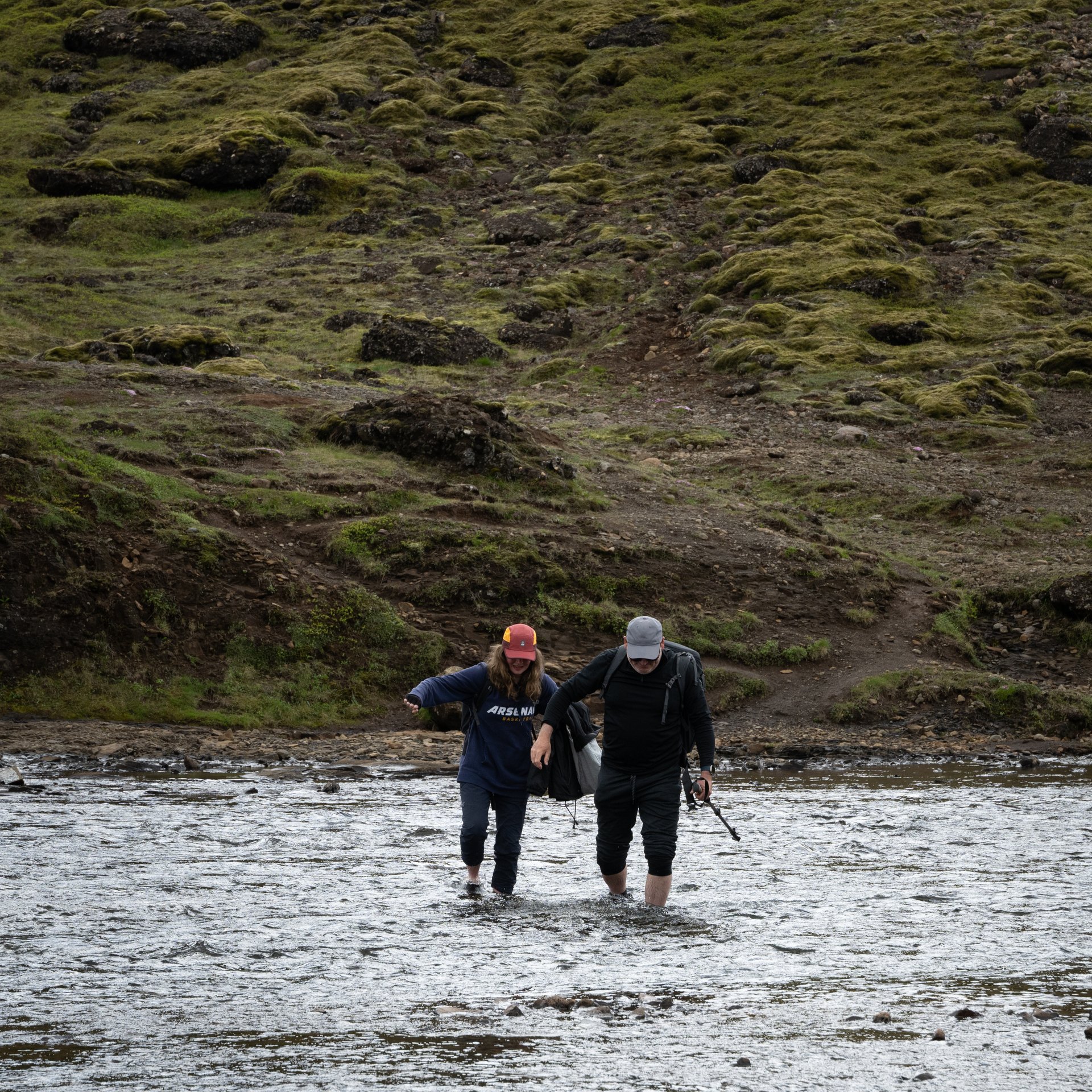 Adventurous hikers crossing river on log bridge during Glymur waterfall trek