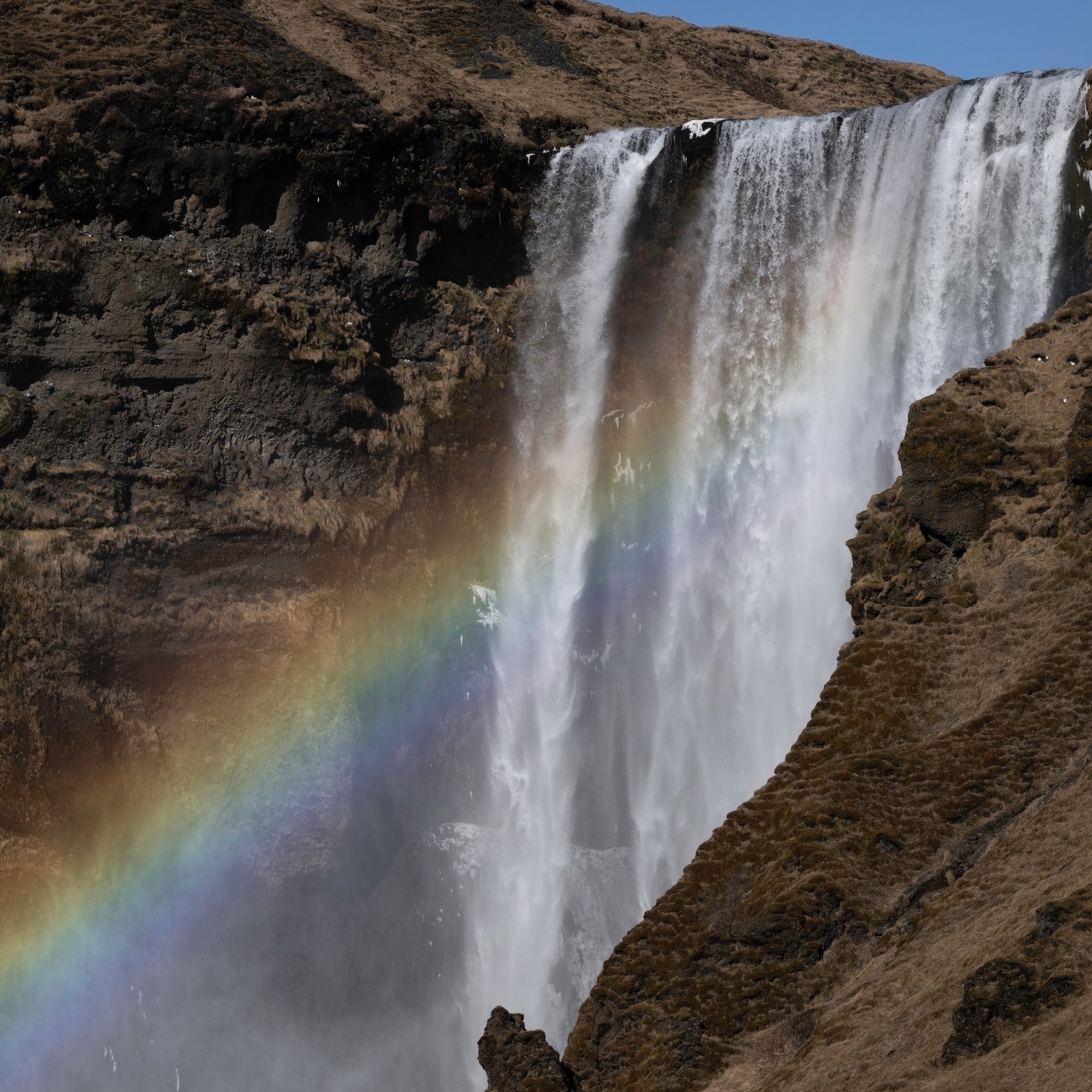 Powerful Skógafoss waterfall with rainbow mist and dramatic cliff formations